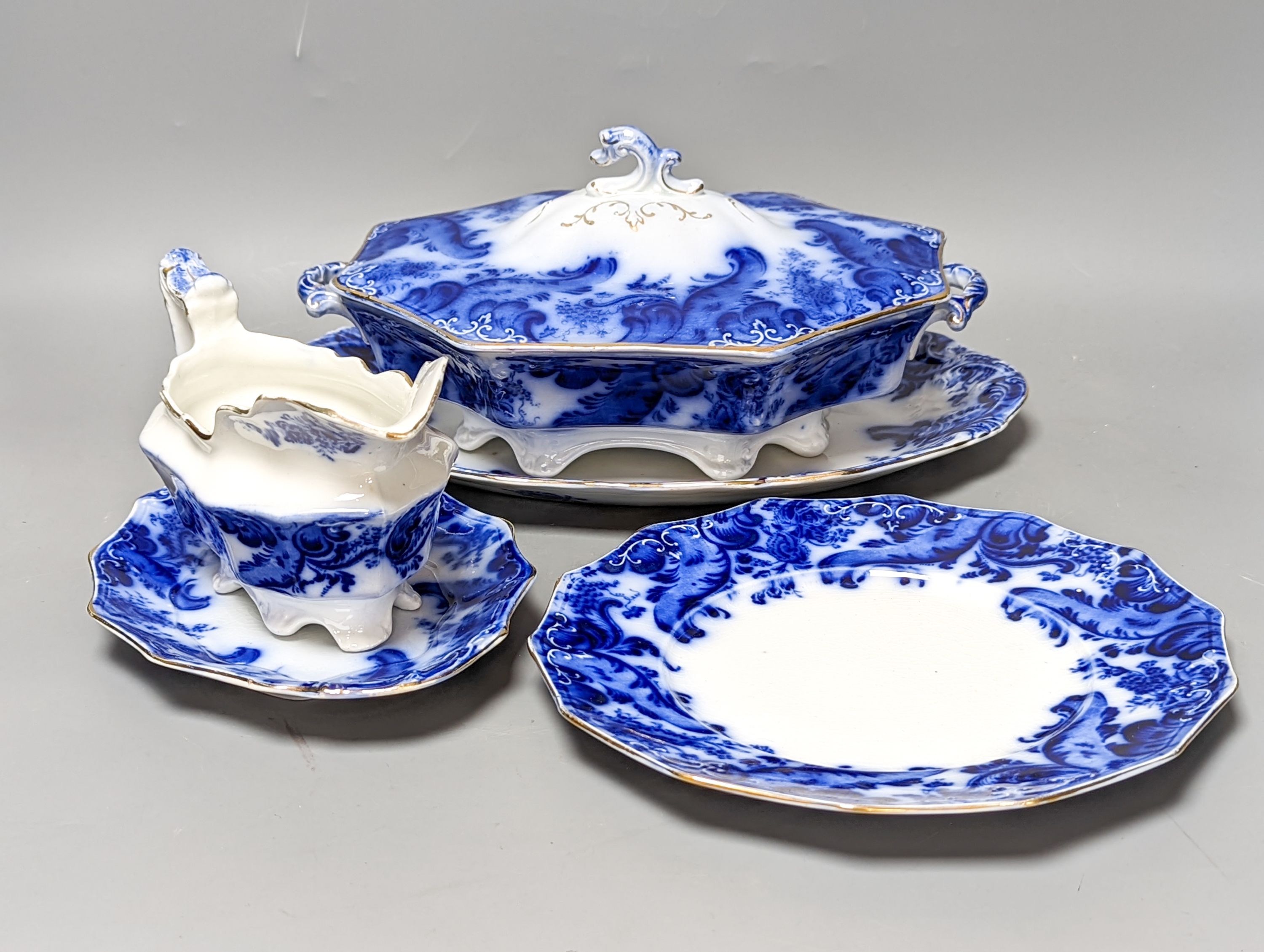 A W. H. Grindley Argyle pattern flow blue dinner service, c.1900 mostly for 12 place settings, two sauce tureens, covers and stands, two vegetable tureens and covers, two gravy boats, and six graduated meat dishes